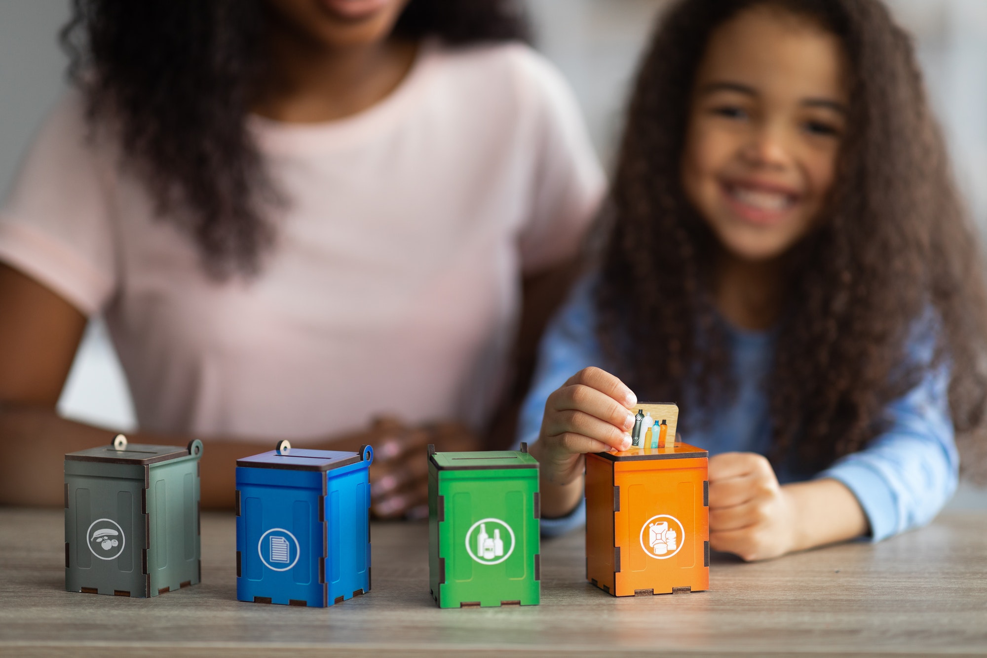 Eco education concept. African American woman playing environmental board game with her daughter